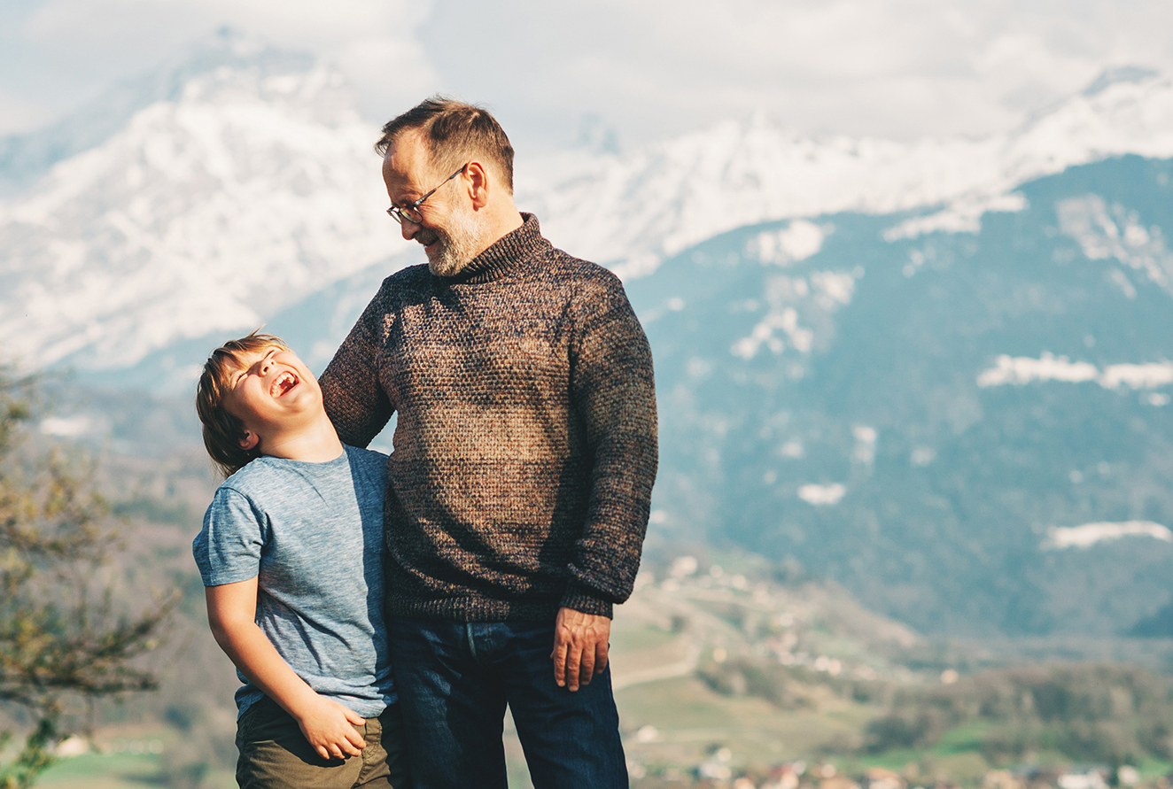 Happy laughing father and son hiking in mountains, active family time.